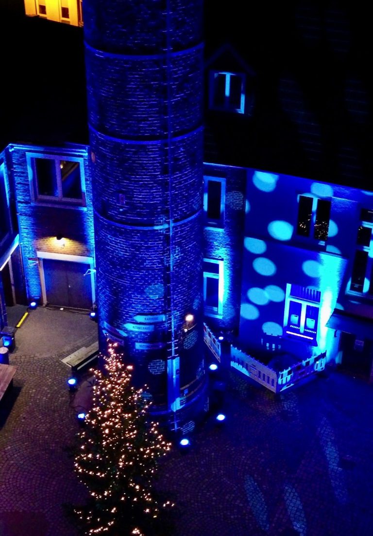 Beleuchteter Turm und Weihnachtsbaum in blauem Licht und festlicher Atmosphäre.